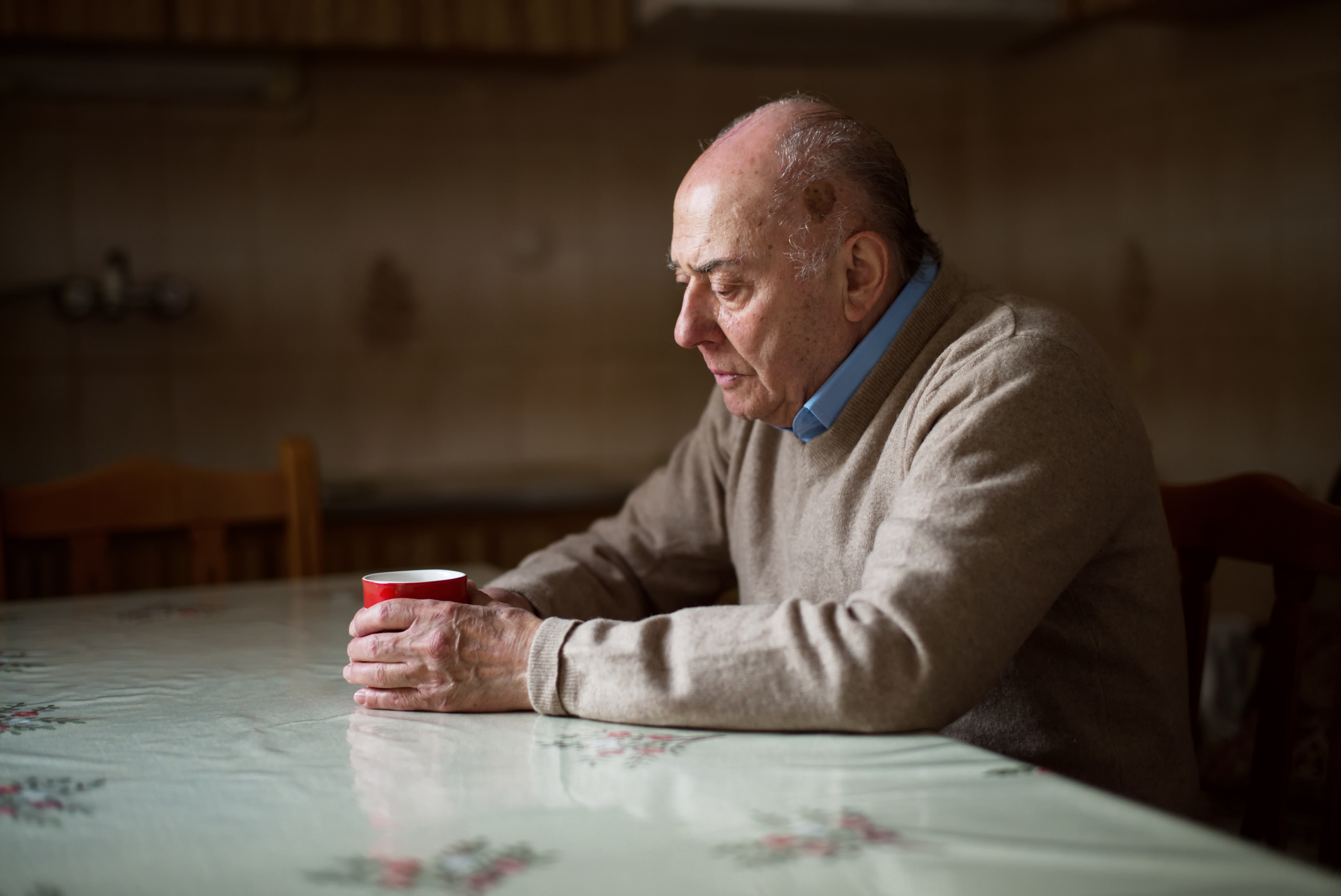 Das Foto zeigt einen Mann in gedr&uuml;ckter Stimmung mit einer Kaffeetasse allein an einem Tisch sitzend. Copyright: Getty Images/Thanasis Zovoilis